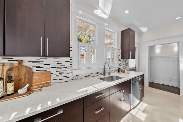 kitchen featuring tasteful backsplash, light stone counters, stainless steel dishwasher, sink, and light hardwood / wood-style flooring