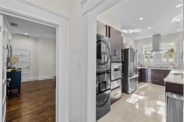 clothes washing area with light hardwood / wood-style floors and stacked washer and clothes dryer