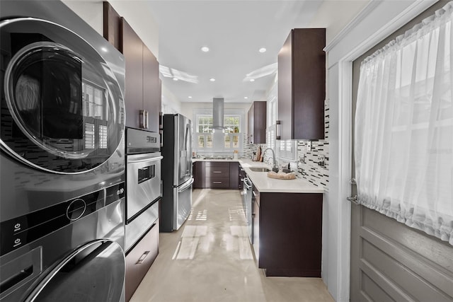 kitchen featuring sink, stainless steel appliances, ventilation hood, backsplash, and stacked washer and dryer