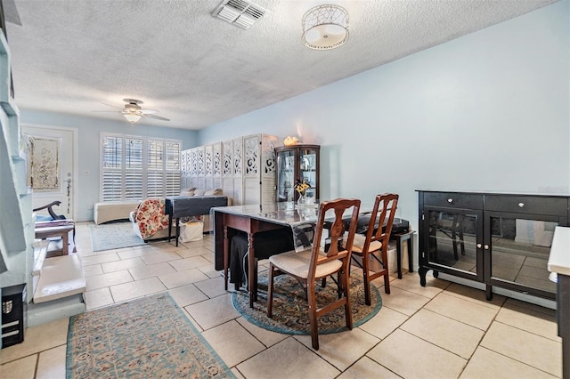 dining area featuring ceiling fan, light tile patterned floors, and a textured ceiling