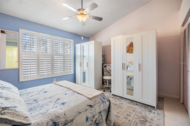 tiled bedroom with a textured ceiling, ceiling fan, a closet, and lofted ceiling