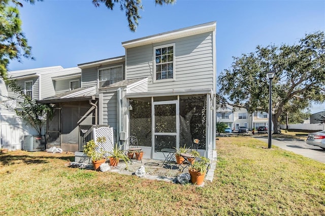 exterior space featuring a sunroom, central AC unit, and a lawn