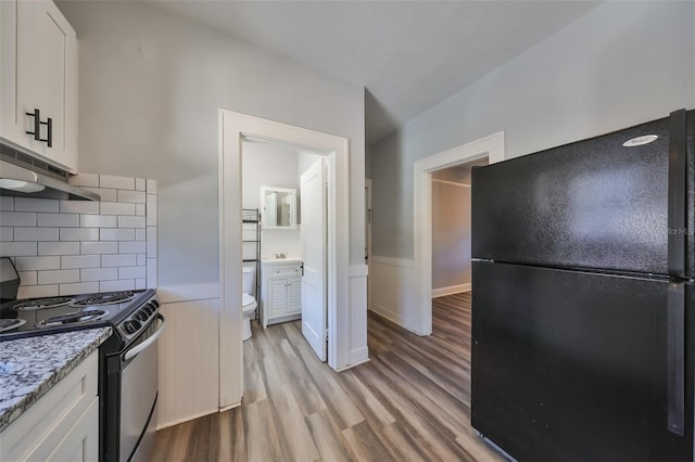 kitchen featuring backsplash, black appliances, white cabinets, light hardwood / wood-style floors, and light stone counters