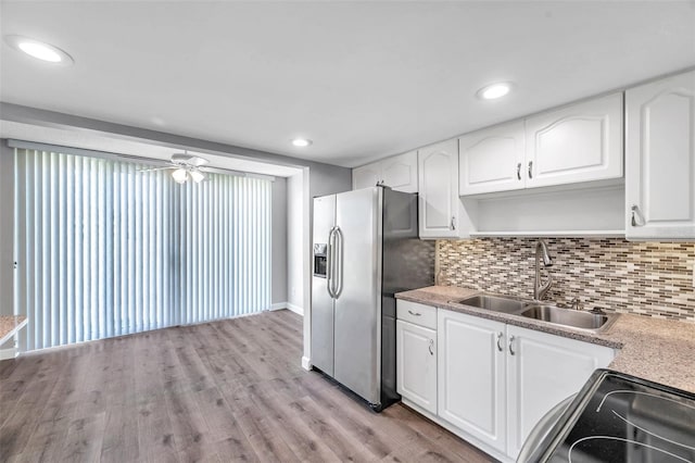 4915 Bay St NE Unit 123, Saint Petersburg, FL 33703 - kitchen featuring sink, decorative backsplash, stainless steel fridge, light wood-type flooring, and white cabinetry