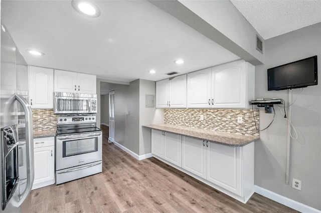 4915 Bay St NE Unit 123, Saint Petersburg, FL 33703 - kitchen with tasteful backsplash, light hardwood / wood-style flooring, white cabinets, and stainless steel appliances