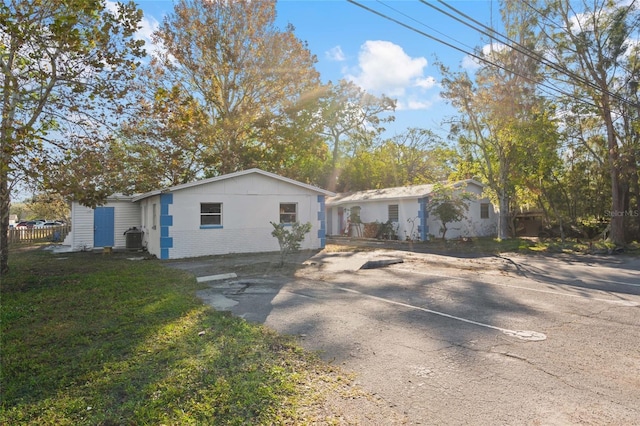 exterior space featuring central air condition unit and a front lawn