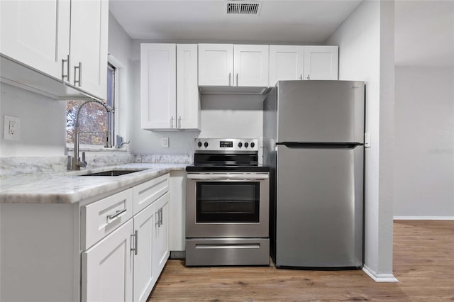 kitchen featuring stainless steel appliances, white cabinetry, and sink