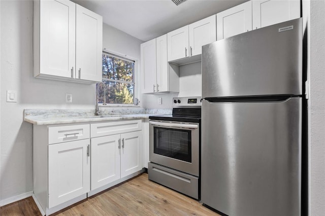 kitchen featuring white cabinetry, sink, light hardwood / wood-style floors, and appliances with stainless steel finishes