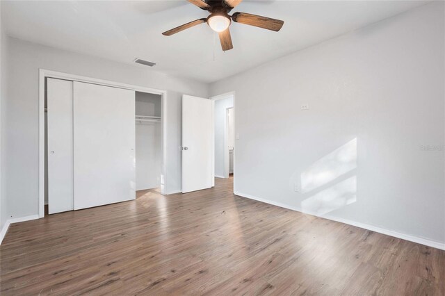 unfurnished bedroom featuring hardwood / wood-style flooring, ceiling fan, and a closet