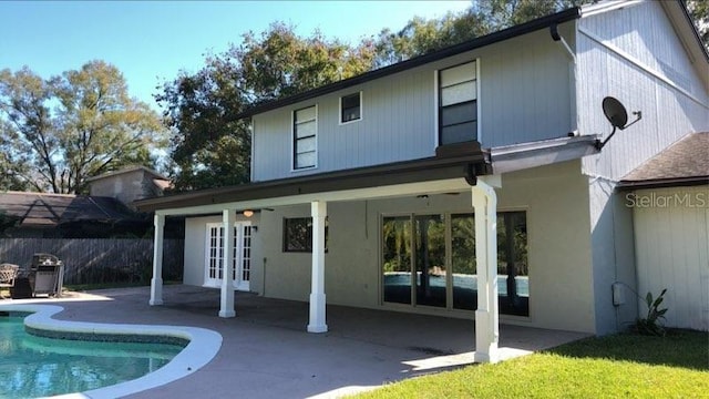 back of property featuring french doors, a fenced in pool, and a patio