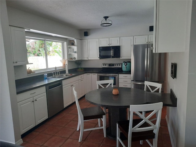 kitchen featuring appliances with stainless steel finishes, white cabinets, dark tile patterned floors, and sink