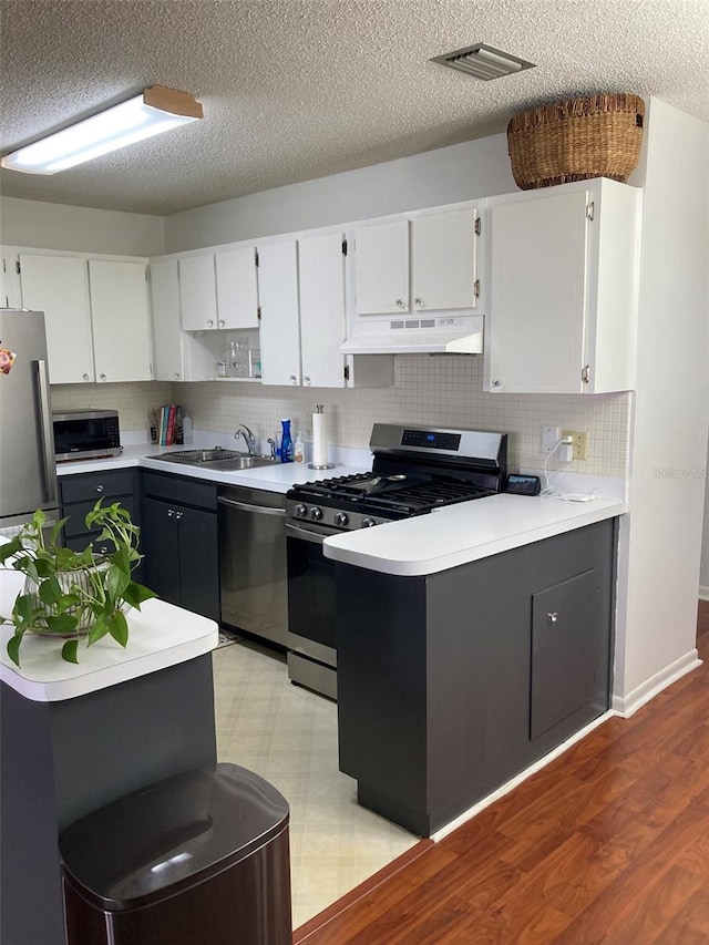 kitchen featuring sink, decorative backsplash, appliances with stainless steel finishes, light hardwood / wood-style floors, and white cabinetry