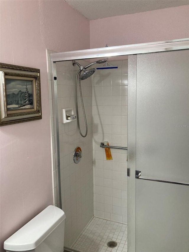 bathroom featuring toilet, an enclosed shower, and a textured ceiling