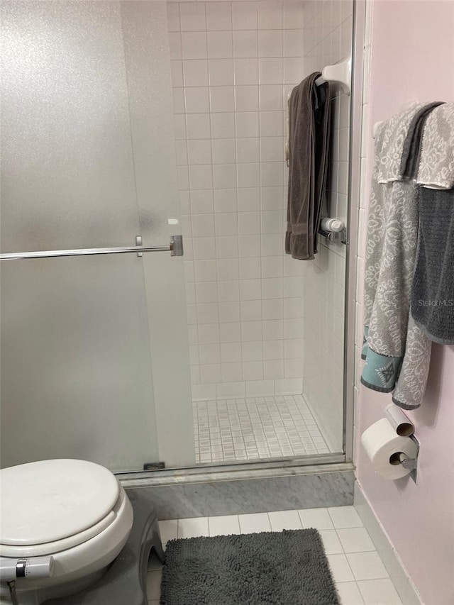 bathroom with tile patterned flooring, toilet, and walk in shower