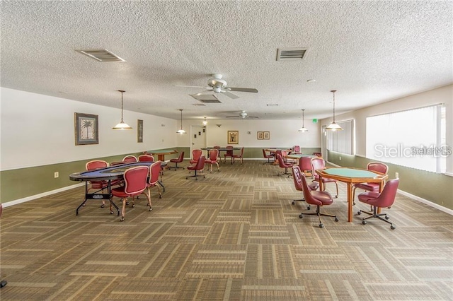 carpeted dining room with a textured ceiling and ceiling fan