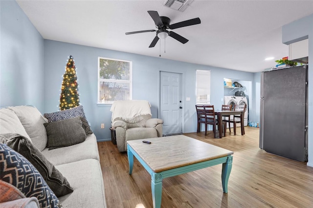 living room featuring washer / clothes dryer, light hardwood / wood-style flooring, and ceiling fan