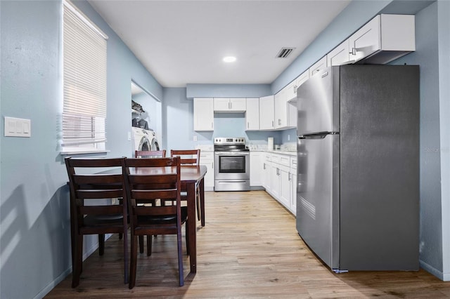 kitchen with white cabinets, stainless steel appliances, and light hardwood / wood-style flooring