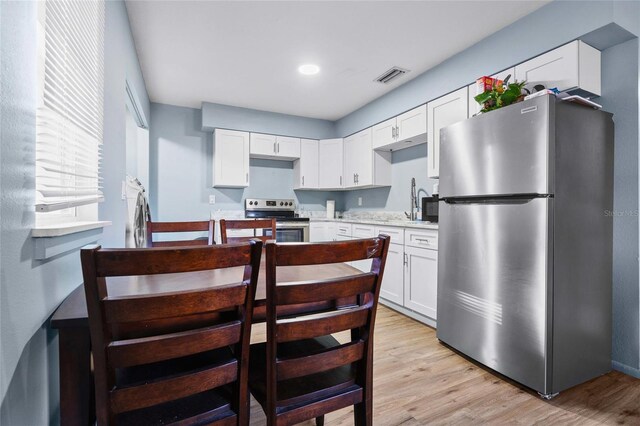 kitchen featuring white cabinets, appliances with stainless steel finishes, and light hardwood / wood-style flooring