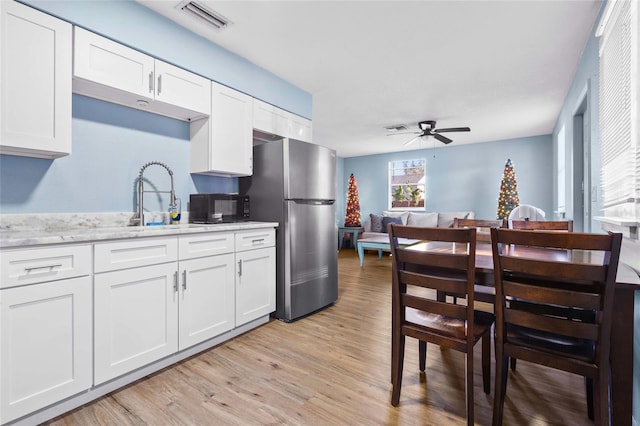 kitchen with white cabinetry, stainless steel refrigerator, and light hardwood / wood-style flooring