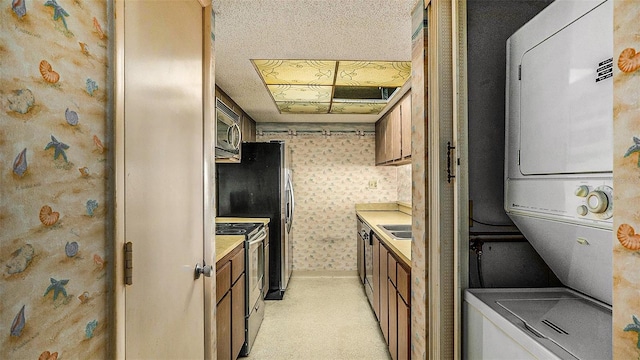 kitchen with light carpet, stacked washing maching and dryer, a textured ceiling, and appliances with stainless steel finishes