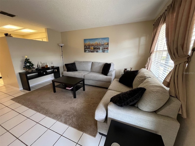 living area with visible vents, a textured ceiling, and light tile patterned flooring