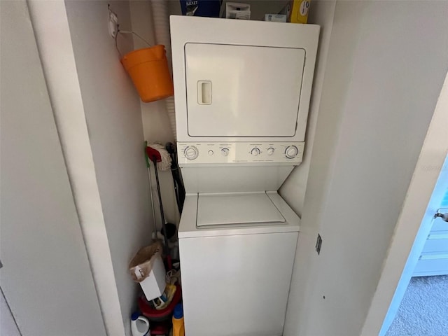 clothes washing area featuring stacked washer / dryer and baseboards