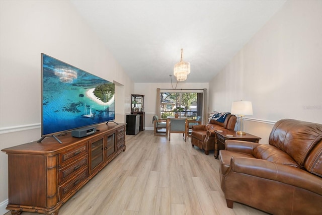 living room featuring a notable chandelier, lofted ceiling, and light hardwood / wood-style flooring