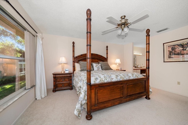 carpeted bedroom featuring ceiling fan, a textured ceiling, and ensuite bath