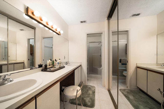 bathroom with tile patterned floors, vanity, a textured ceiling, toilet, and a shower with shower door