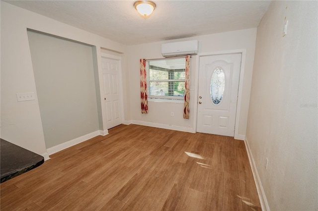 foyer with light wood-type flooring and a wall mounted AC