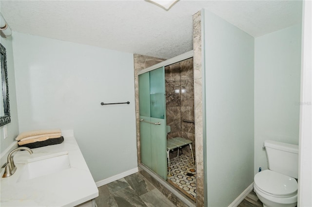 bathroom featuring vanity, a textured ceiling, toilet, and a shower with shower door