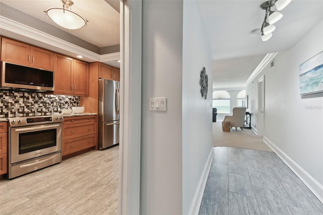 kitchen with backsplash, light hardwood / wood-style flooring, ornamental molding, and appliances with stainless steel finishes