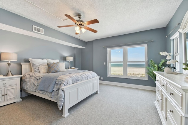 bedroom featuring ceiling fan, light colored carpet, a textured ceiling, and multiple windows