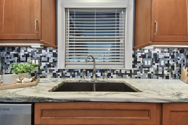 kitchen featuring backsplash, light stone countertops, sink, and stainless steel dishwasher