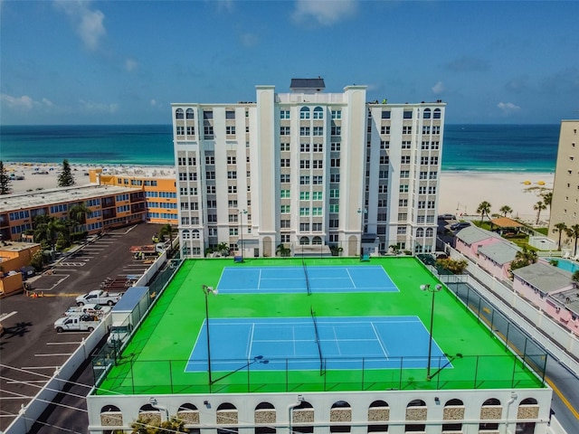 view of sport court with a water view and a beach view