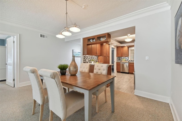 dining space featuring crown molding, visible vents, baseboards, light colored carpet, and a textured ceiling