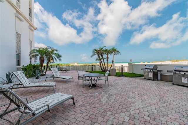 view of patio with a water view, fence, and a grill