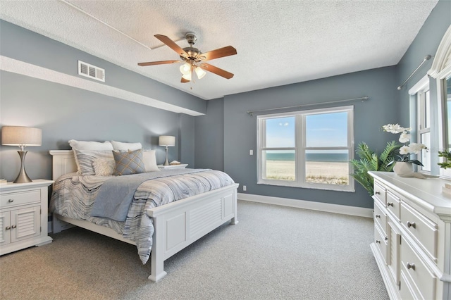 bedroom with light colored carpet, a textured ceiling, a ceiling fan, baseboards, and visible vents