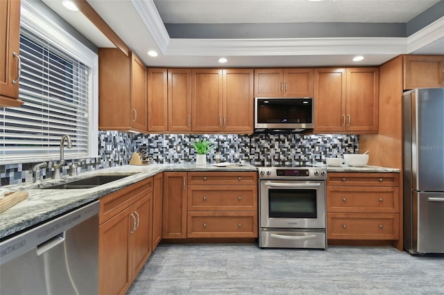 kitchen with stainless steel appliances, brown cabinetry, a sink, and tasteful backsplash