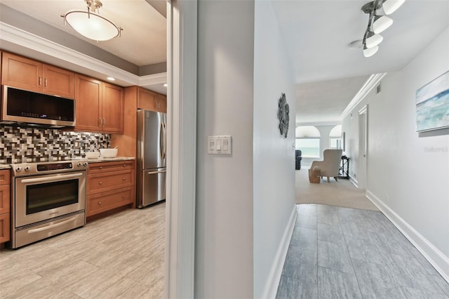kitchen with crown molding, baseboards, brown cabinets, tasteful backsplash, and appliances with stainless steel finishes