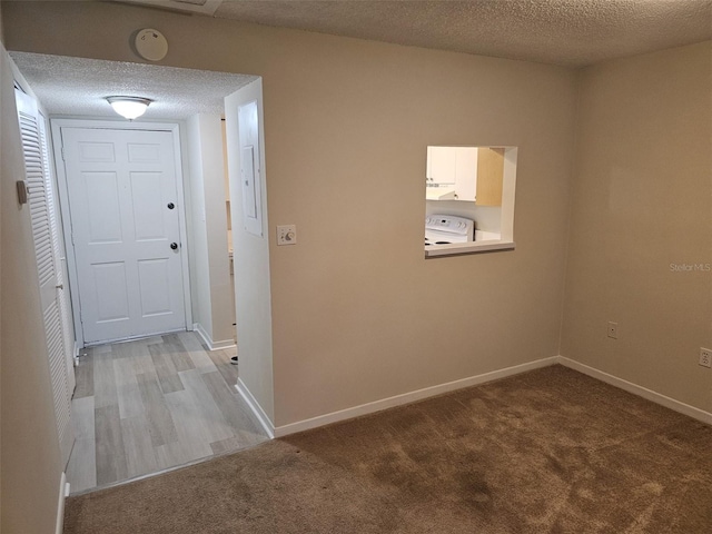 hall with a textured ceiling and light colored carpet