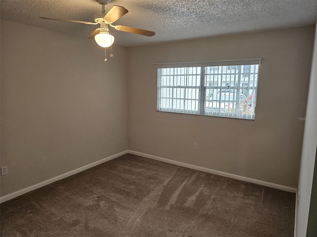 spare room featuring ceiling fan, dark carpet, and a textured ceiling