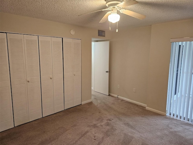 unfurnished bedroom with ceiling fan, light colored carpet, a textured ceiling, and a closet