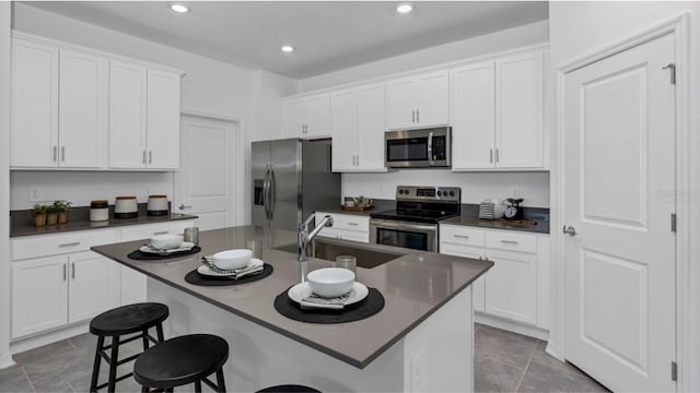 kitchen with a center island with sink, a kitchen breakfast bar, sink, white cabinetry, and stainless steel appliances