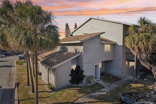 property exterior at dusk featuring a yard