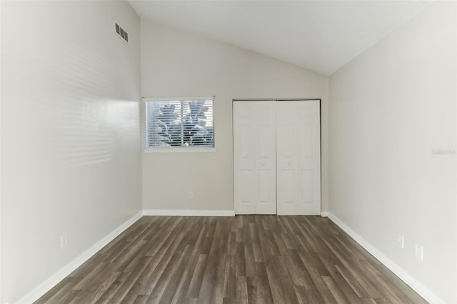 unfurnished bedroom featuring dark hardwood / wood-style floors, a closet, and lofted ceiling