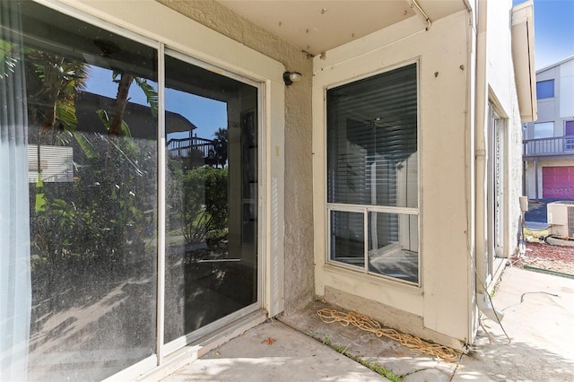 view of exterior entry featuring a patio area and central air condition unit