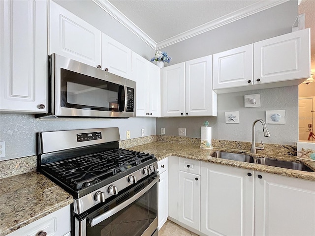 kitchen with light stone countertops, stainless steel appliances, crown molding, sink, and white cabinets