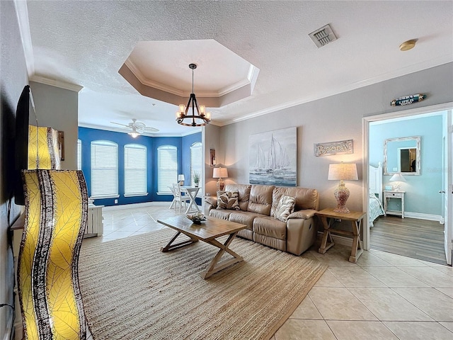 tiled living room featuring a textured ceiling, crown molding, a tray ceiling, and ceiling fan with notable chandelier