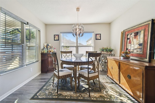 dining area featuring a textured ceiling, dark hardwood / wood-style floors, and an inviting chandelier